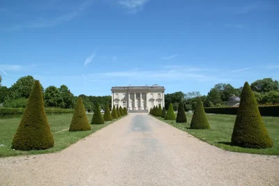 Le château de pignerolle au centre de l’image, entouré du parc, sous un grand ciel bleu
