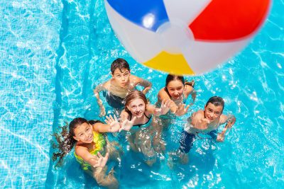 5 enfants dans une piscine en train de jouer avec un ballon gonflable